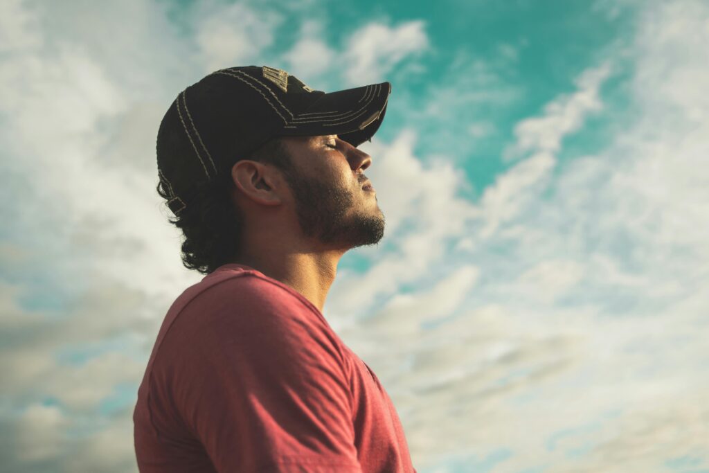 pexels-photo-810775-810775 A man enjoys outdoor relaxation and mindfulness beneath a bright, cloudy sky, exuding calm and peace.